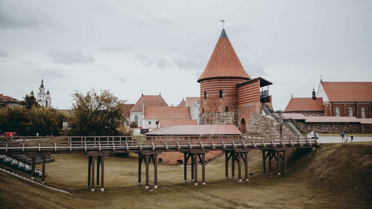 Castel gotic cu turnuri ascuțite și un pod lung de lemn, așezat pe o stâncă deasupra unui pârâu