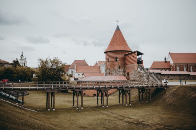 Castel gotic cu turnuri ascuțite și un pod lung de lemn, așezat pe o stâncă deasupra unui pârâu