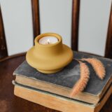 Cărți vechi și o lumânare pe un birou de lemn, evocând biblioteca unui cărturar de altădată