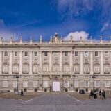 Fațada unui palat baroc dintr-o piață istorică, cu ferestre înalte și portal sculptat